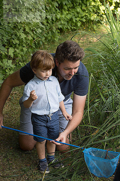 Vater und Kind schauen im Fischernetz