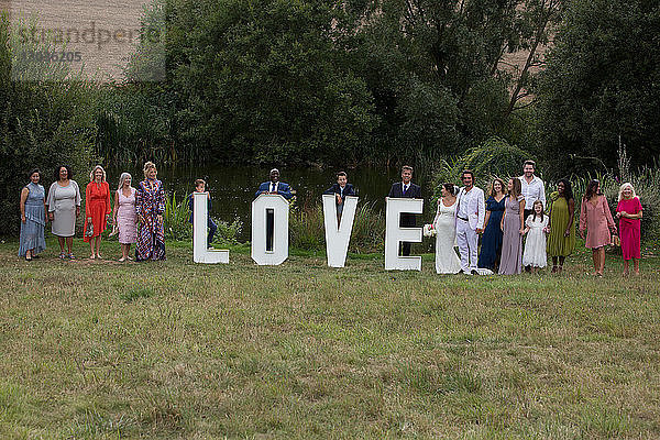 Hochzeitsgäste posieren hinter Liebeswort