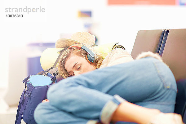 Junge Frau am Flughafen  schläft auf einem Sitzplatz in der Abflughalle