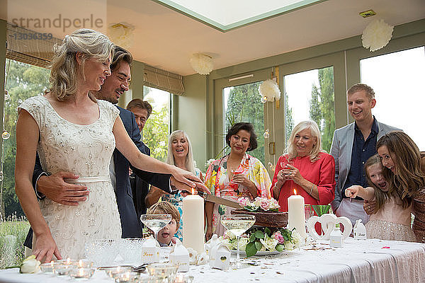 Neuvermählte schneiden Hochzeitstorte beim Empfang an