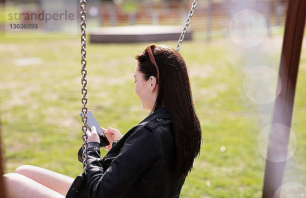 Teenager-Mädchen schreibt beim Schaukeln SMS