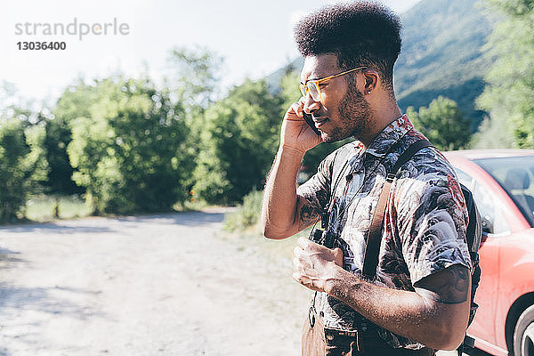 Junger männlicher Wanderer auf ländlichem Feldweg beim Telefonieren mit dem Smartphone  Primaluna  Trentino-Südtirol  Italien