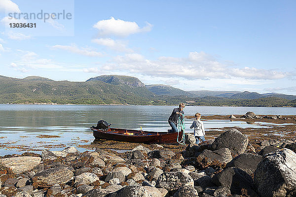 Erwachsener Mann übergibt Seil vom Ruderboot an den Sohn  Aure  More og Romsdal  Norwegen