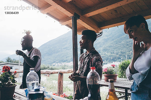 Drei junge erwachsene Freunde machen eine Pause auf einer ländlichen Veranda