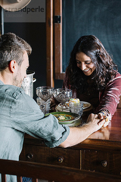 Romantisches junges Paar beim Essen  Hände über den Tisch haltend