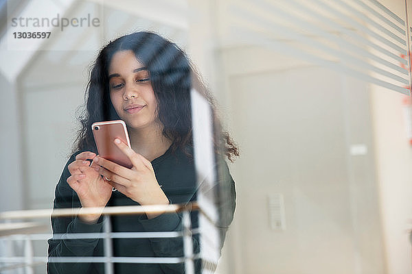 Teenager-Mädchen liest Textnachricht auf Handy an Glaswand