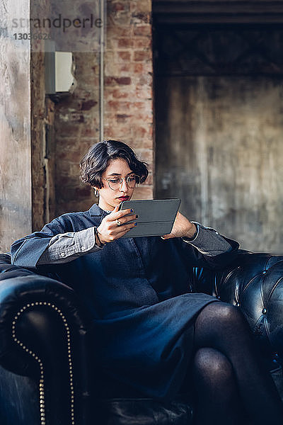 Frau im Sessel mit digitalem Tablett