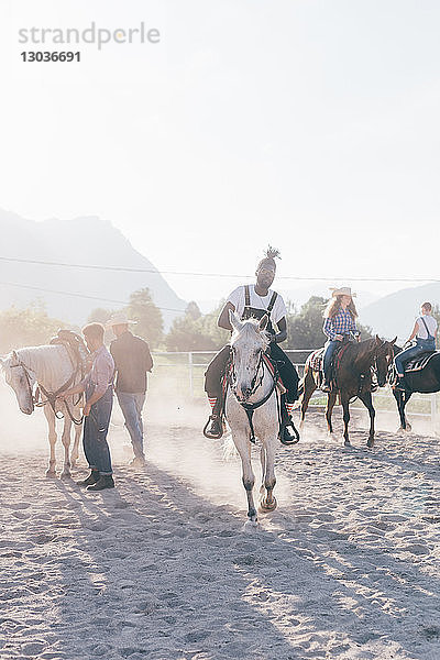 Junger Hipster-Mann mit Freunden reitet Pferde in ländlicher Reitarena  Primaluna  Trentino-Südtirol  Italien
