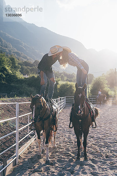 Cowgirl und Freund stehen zu Pferd und küssen sich auf dem Reitplatz  Primaluna  Trentino-Südtirol  Italien