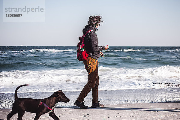 Mittelgroßer erwachsener Mann geht mit seinem Hund am Strand spazieren  Odessa  Odeska Oblast  Ukraine