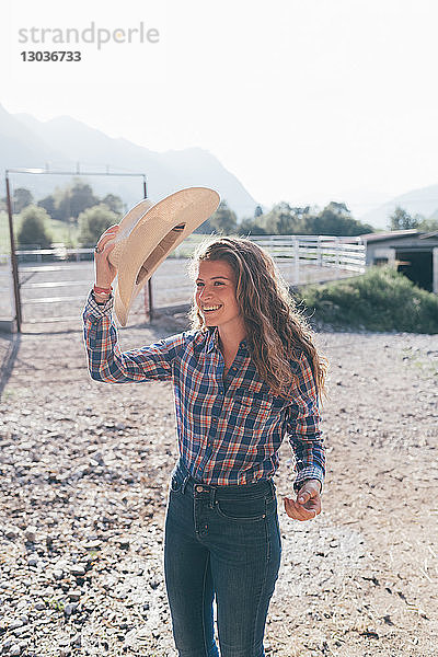 Cowgirl zieht Stetson auf ländlichem Reitplatz an