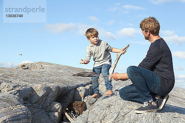 Junge und Vater bereiten ein Lagerfeuer auf dem Einlassfelsen vor  Aure  More og Romsdal  Norwegen