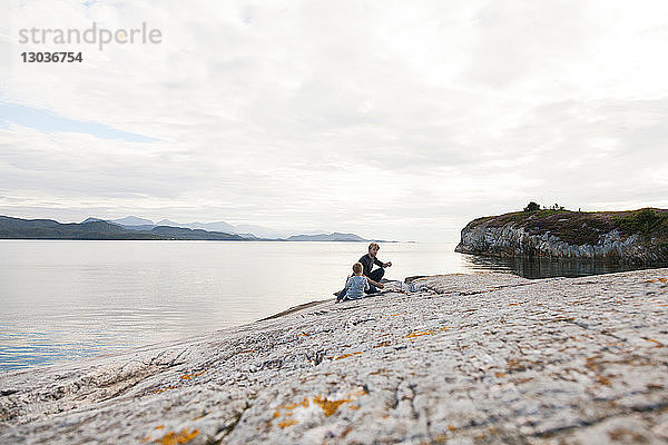 Junge und Vater essen Essen auf einem Einlauffelsen  Aure  More og Romsdal  Norwegen