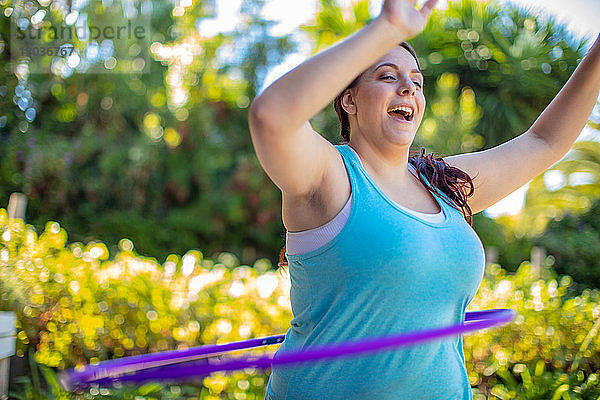 Frau übt mit Hula-Hoop-Reifen im Garten