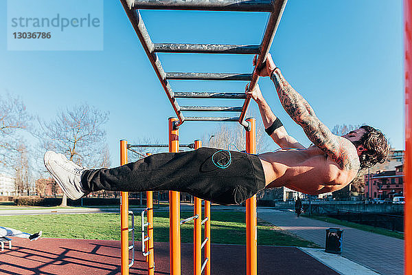Mann benutzt horizontale Leiter im Fitnessstudio im Freien