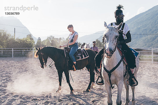 Junger Hipster-Mann und Frau reiten auf Pferden in ländlicher Reitarena  Primaluna  Trentino-Südtirol  Italien