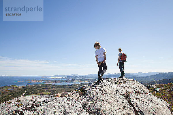 Junge und Vater schauen von einer Felsformation über die Landschaft hinaus  Aure  More og Romsdal  Norwegen