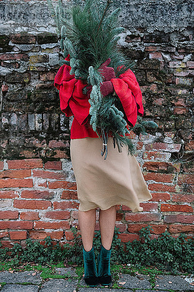 Junge Frau vor alter Backsteinmauer mit Weihnachtsbaum