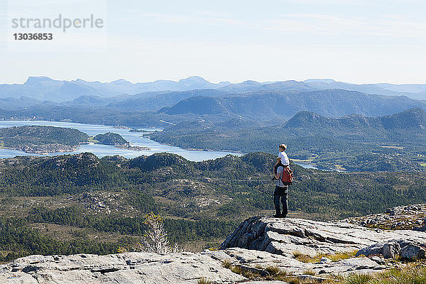 Junge und Vater blicken von einer Felsformation auf die Fjordlandschaft  Aure  More og Romsdal  Norwegen