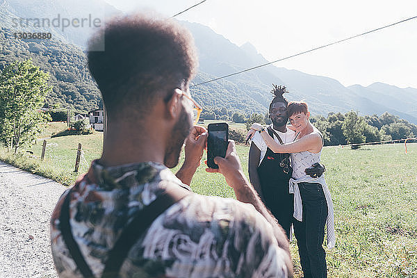 Junger Mann auf ländlichem Feldweg fotografiert Freunde auf Smartphone  Primaluna  Trentino-Südtirol  Italien