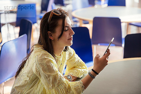 Teenager-Mädchen liest Textnachrichten auf Handy in der Schule