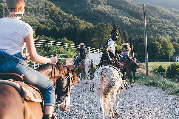 Erwachsene Freunde reiten auf Pferden auf ländlichem Feldweg  Rückansicht  Primaluna  Trentino-Südtirol  Italien