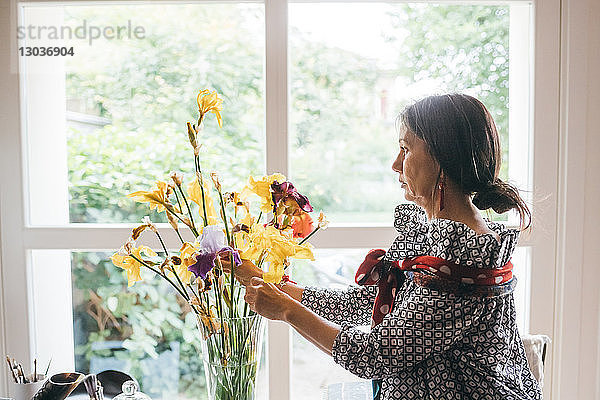Frau arrangiert Blumen in Vase