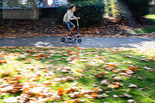 Junge fährt Roller im Park