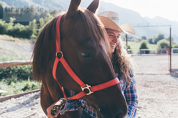 Junges Cowgirl führt Pferd in ländlicher Reithalle