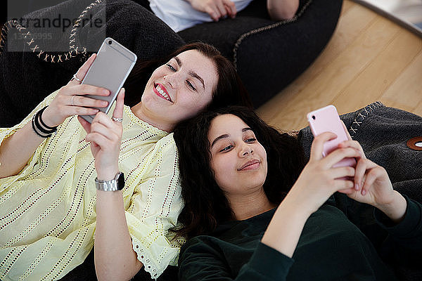 Schulfreunde liegen auf Sitzsäcken und schreiben in der Schule SMS