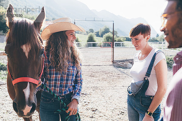 Junges Cowgirl mit Pferd auf ländlichem Reitplatz