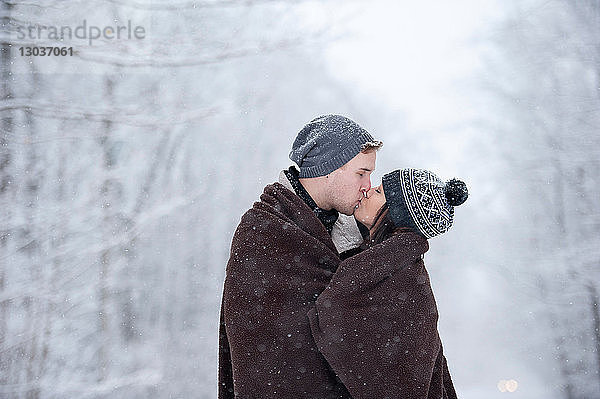 Romantisches junges Paar küsst sich im verschneiten Wald  Ontario  Kanada