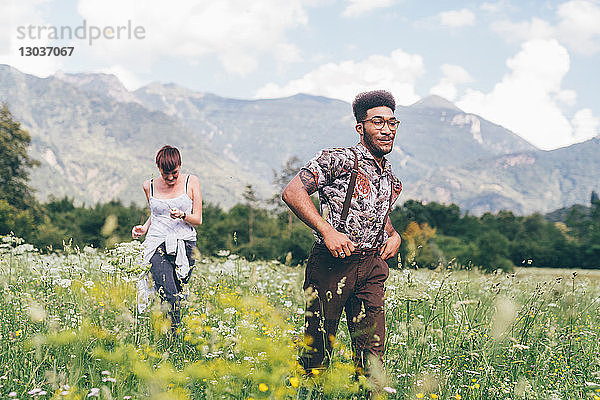 Junger Mann und Frau rasen durch eine Wildblumenwiese  Primaluna  Trentino-Südtirol  Italien