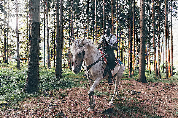 Cooler junger Mann reitet im Wald  Primaluna  Trentino-Südtirol  Italien