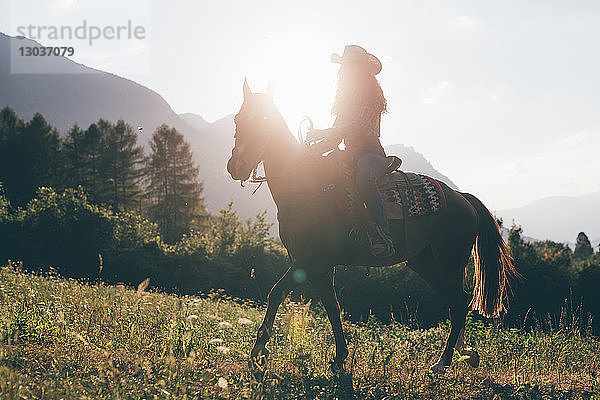 Cowgirl Reiten im Feld  hinterleuchtet  Primaluna  Trentino-Südtirol  Italien