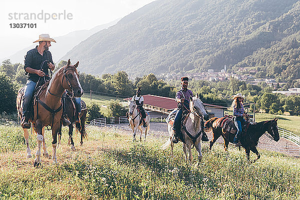 Junge Erwachsene reiten Pferde in ländlicher Landschaft  Primaluna  Trentino-Südtirol  Italien