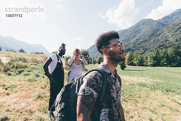 Drei junge Wanderfreunde blicken von der Feldlandschaft auf  Primaluna  Trentino-Südtirol  Italien