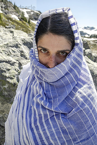 Porträt einer Frau im Freien  eingewickelt in ein Handtuch nach dem Schwimmen in einem See in den Bergen