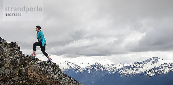 Seitenansicht einer mittelgroßen erwachsenen Frau beim Wandern auf einem felsigen Bergrücken in den Bergen  Whistler  British Columbia  Kanada