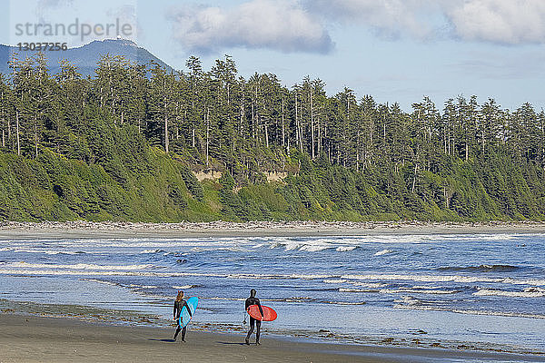 Zwei Surfer in dicken Neoprenanzügen bereiten sich darauf vor  in der Florencia Bay im Pacific Rim Park in Tofino  British Columbia  Kanada  ins Wasser zu gehen