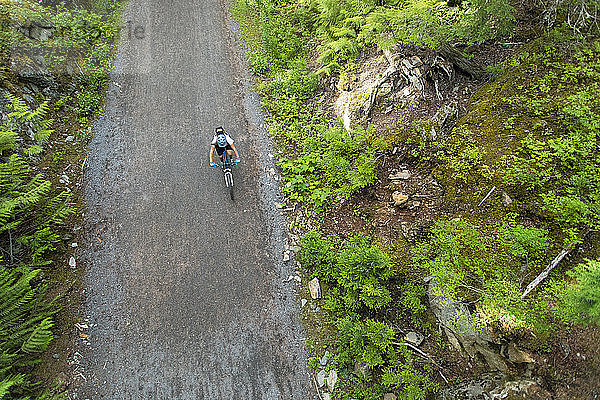 Blick von oben auf eine abenteuerlustige Frau beim Mountainbiken auf einer unbefestigten Straße  Lost Lake Trails  Whistler  British Columbia  Kanada