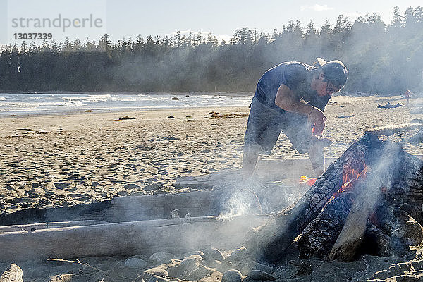 Mann  der am Strand über einem Lagerfeuer Essen zubereitet â€ Tofino  British Columbia  Kanada