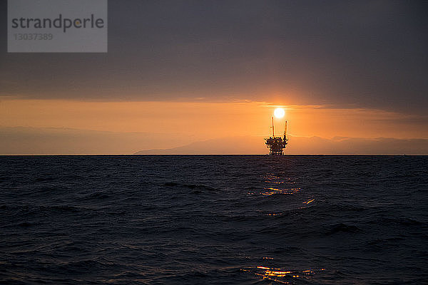 Fernblick auf die Silhouette einer Ölplattform im Meer bei Sonnenuntergang  Ventura  Kalifornien  USA