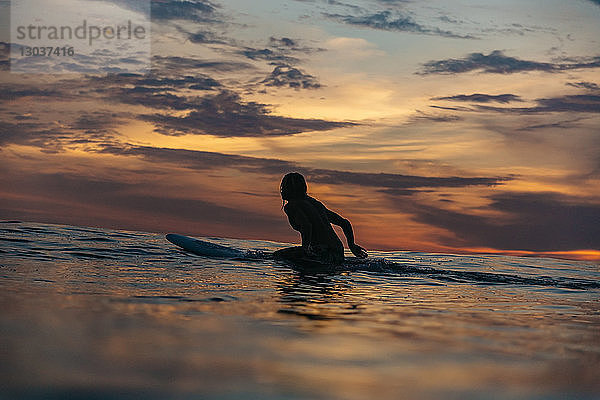 Silhouette einer Surferin im Meer bei Sonnenuntergang â€ Changgu  Bali  Indonesien
