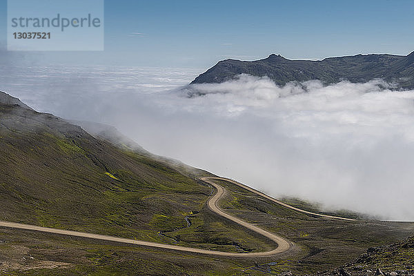 Landschaft mit einer Straße am Hang und Nebel in Borgafjordur Eystri  Island