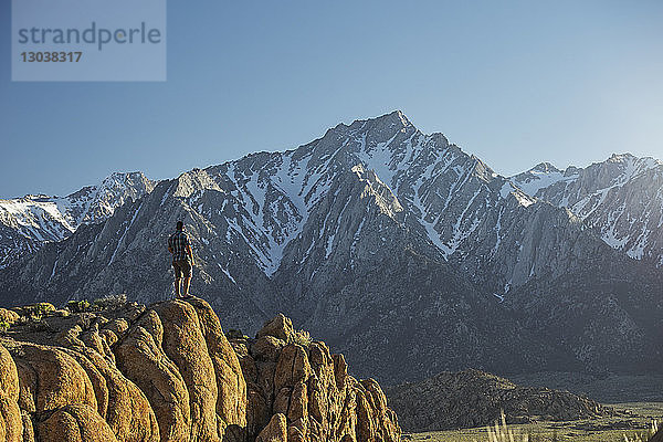 Wanderer in voller Länge mit Blick auf die Aussicht  während er auf einem Bergfelsen steht