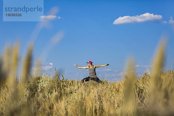 Mann mit ausgestreckten Armen praktiziert Yoga auf dem Feld gegen den Himmel im Bridger-Teton National Forest