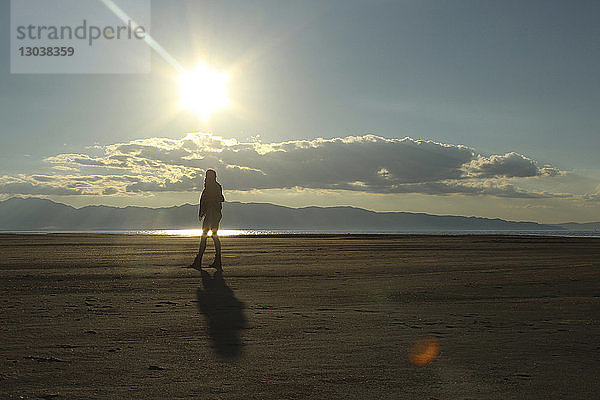 Silhouette einer Frau  die auf Sand am See geht