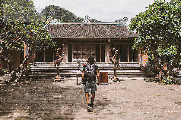 Rückansicht eines Touristen mit Rucksack auf dem Weg zur Pagode