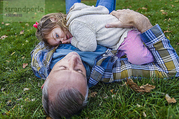 Vater und Tochter liegen auf einem Grasfeld im Park